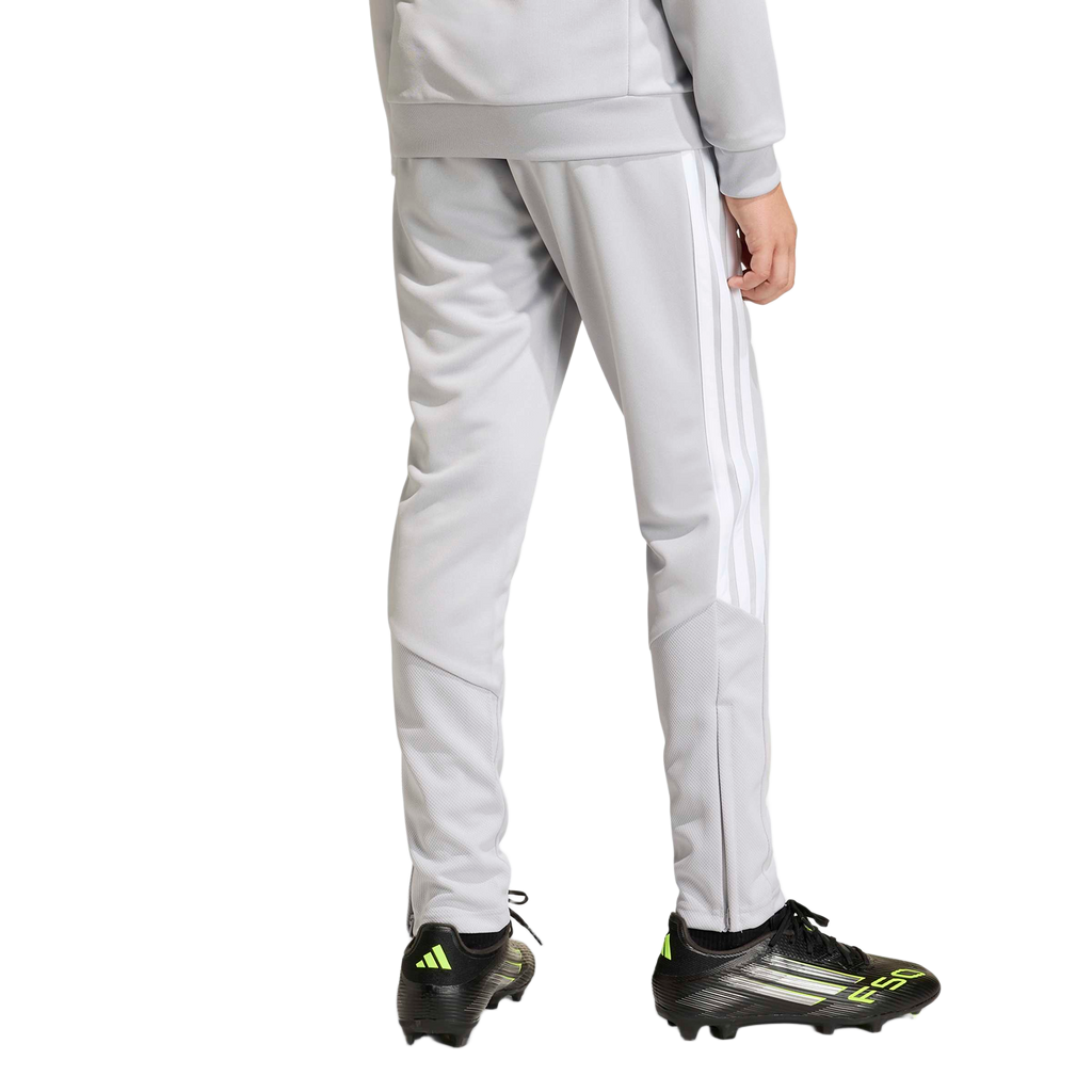 Rear view of a person wearing light gray track pants with white side stripes and black soccer cleats with neon green accents.