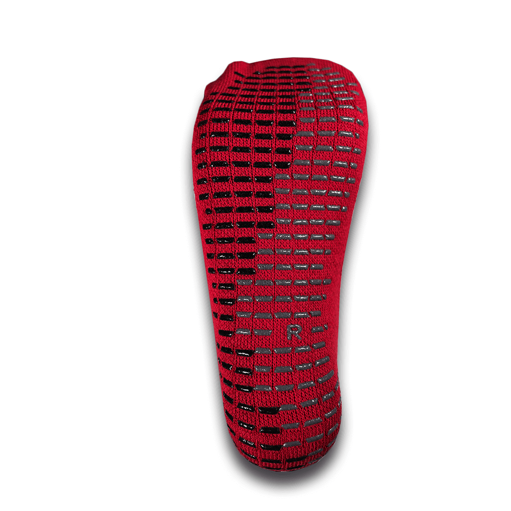 The sole of a red For The Footballer XLR8R Pro No Slip Sock, featuring a dense pattern of black and grey rectangular grip pads and a small letter "R" indicating the right foot.
