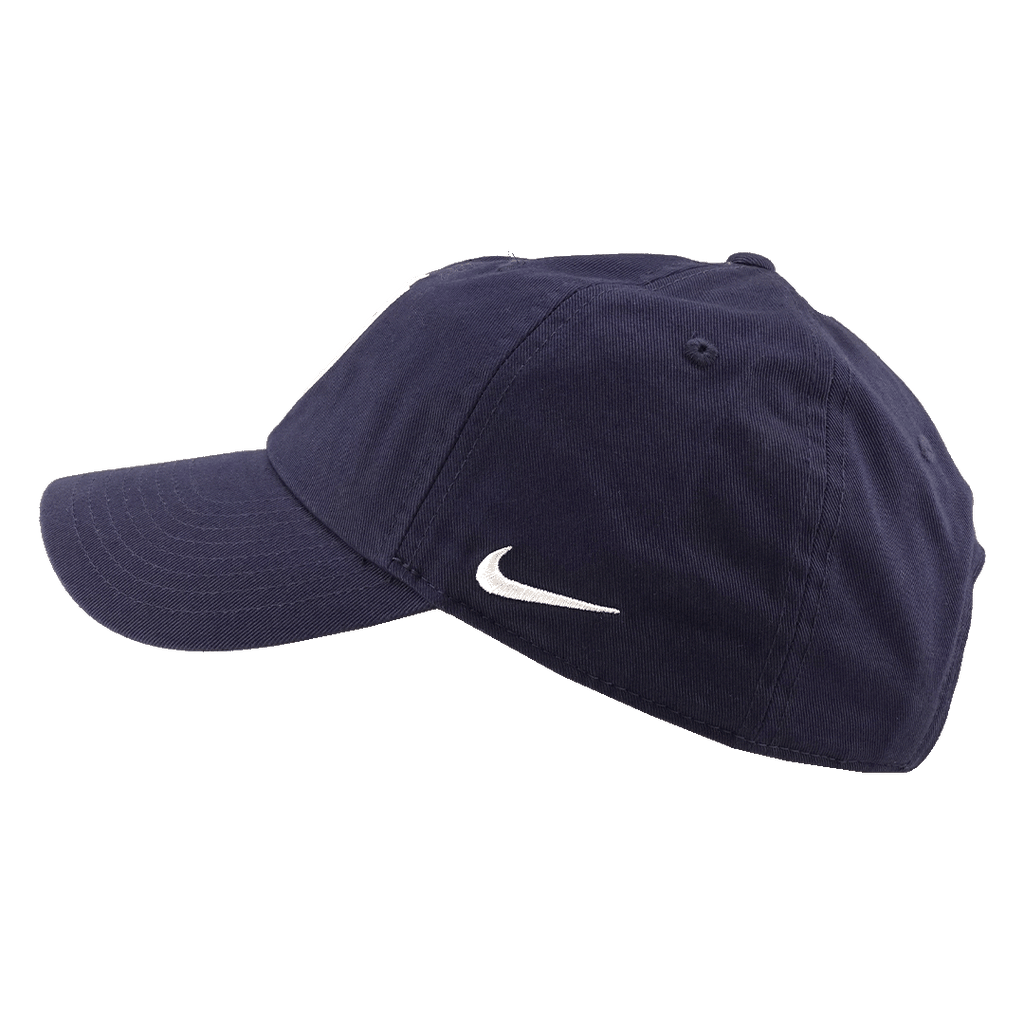 A side view of a navy blue Nike baseball cap with a white swoosh logo, set against a solid green background.