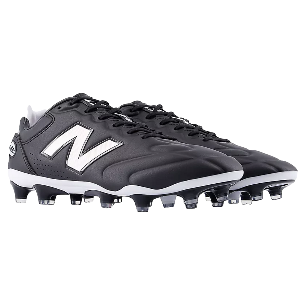 A pair of black and white New Balance soccer cleats featuring the iconic white "N" logo on the side and a studded outsole, set against a black background.