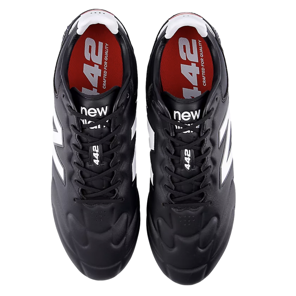 A pair of black New Balance 442 soccer cleats from a top-down perspective, featuring white logos and red insoles with white text.