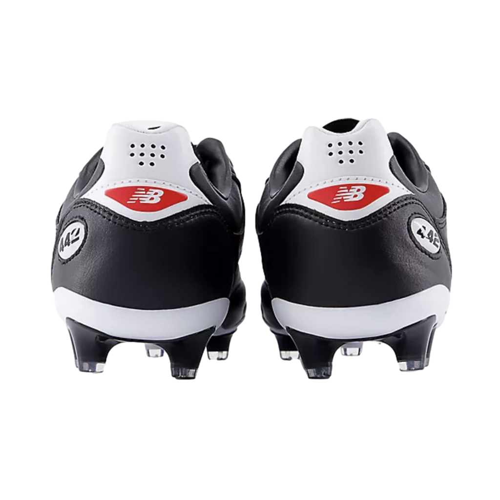 Rear view of black and white New Balance 442 soccer cleats against a black background, featuring red logos on the white heel counters.